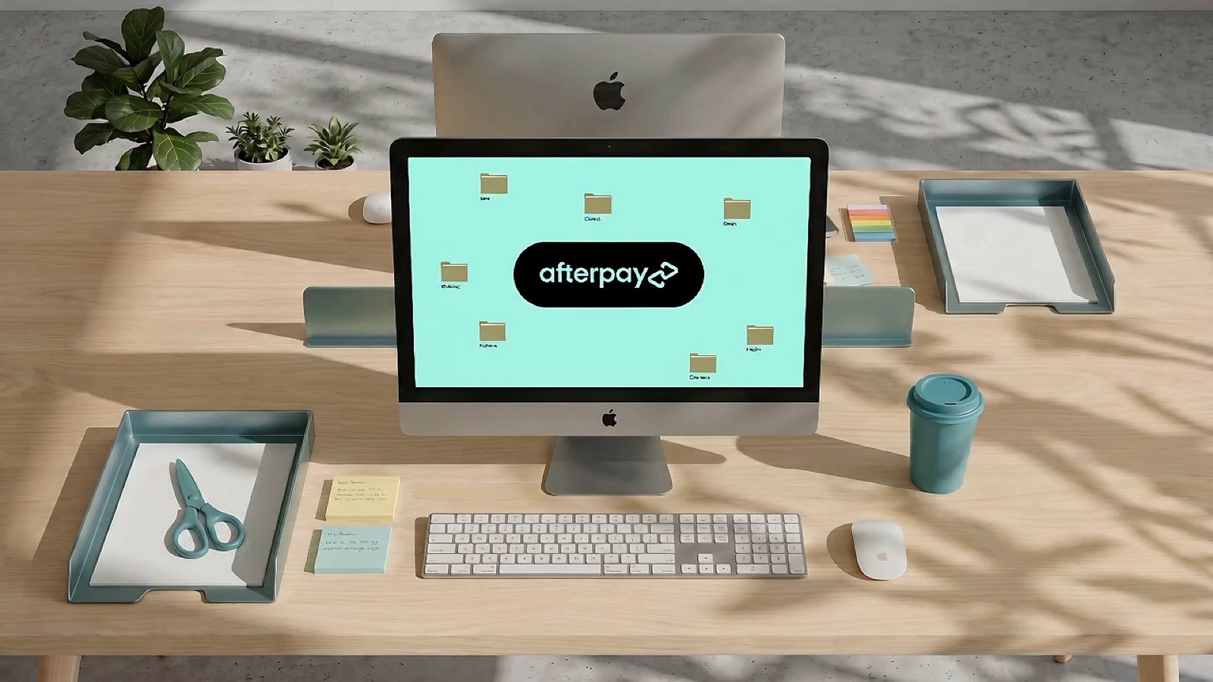 The Afterpay logo on a desktop monitor in a styled mint and timber workspace